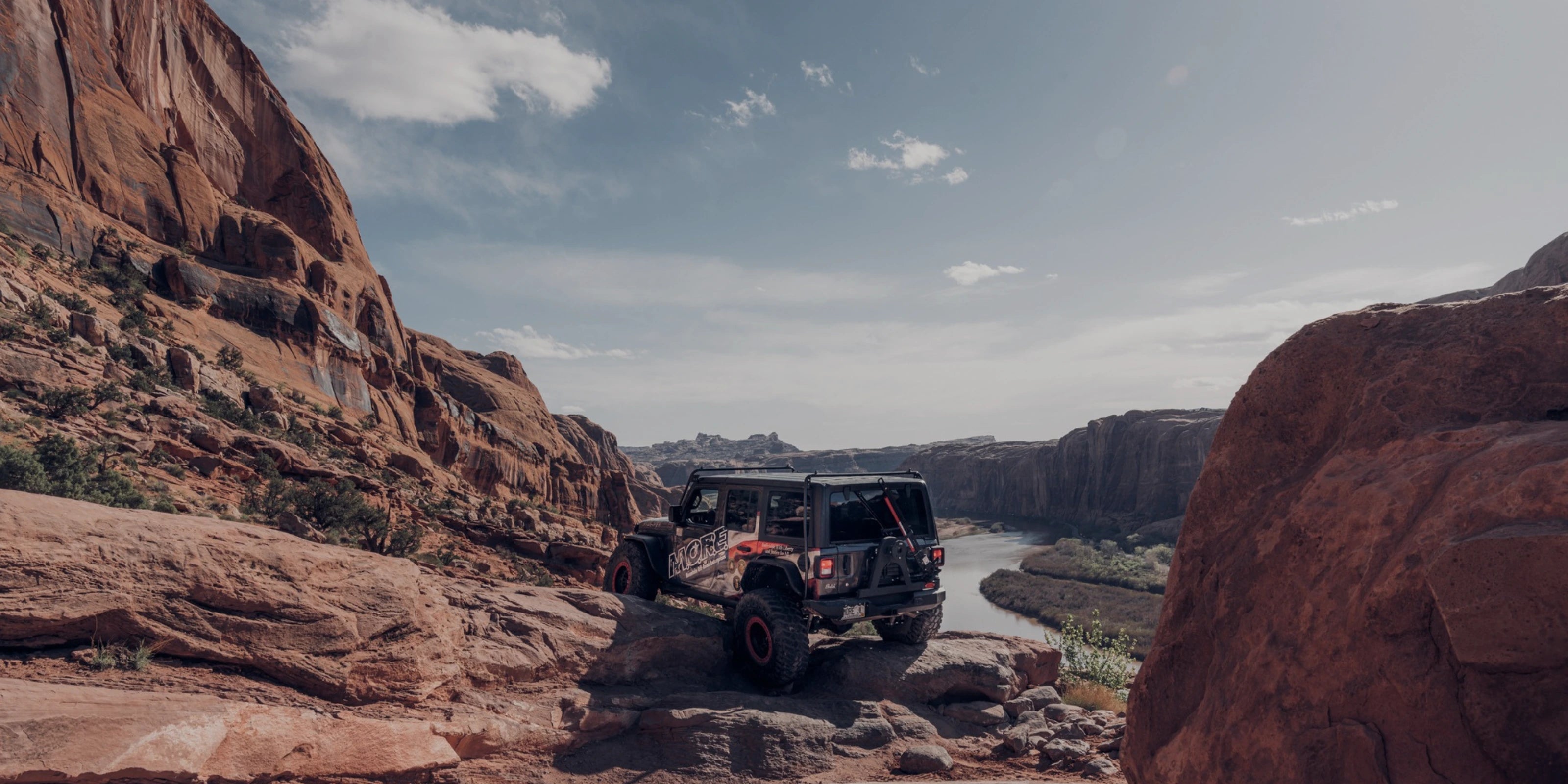 A black Jeep overlooking a vast canyon trail, fully outfitted with jeep wrangler armor and built using parts from the jeep parts catalog for serious off-road exploration.