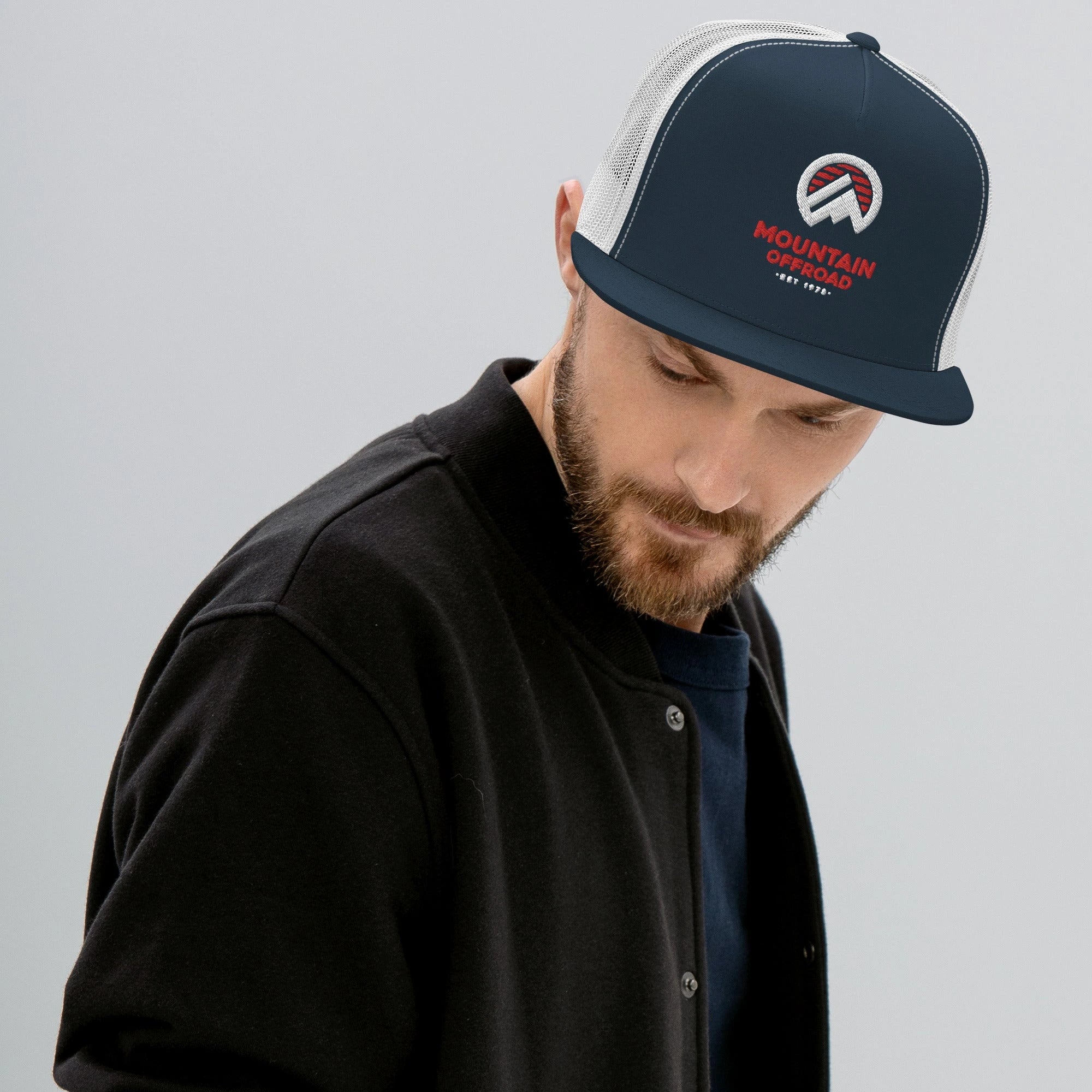 A man wearing a dark snapback hat with the Mountain Offroad logo and mesh back, styled with a black jacket — showcasing lifestyle gear that pairs with jeep wrangler armor and off-road accessories.